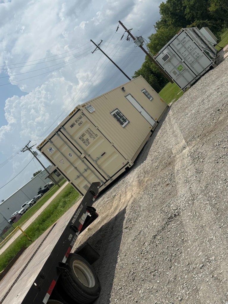Ground level shipping container office tilt bed delivery in Houma, LA at petrochemical jobsite